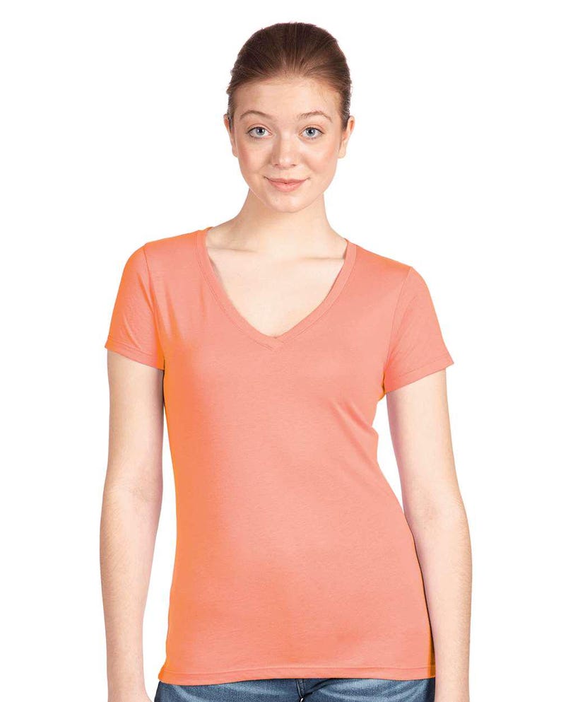 May include: A solid coral-colored short-sleeve t-shirt featuring a deep V-neckline. The garment is constructed from a smooth, lightweight fabric and has a fitted silhouette with short sleeves and a straight hemline at the waist.