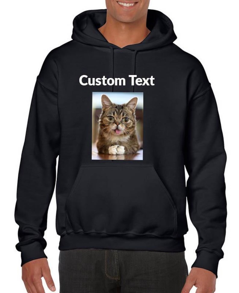 May include: A black hooded sweatshirt featuring a rectangular graphic print on the chest. The print displays a brown tabby cat with its tongue sticking out and the text Custom Text printed in white above the cat image on the black fabric.