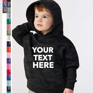 May include: A black and grey camouflage hoodie for a child with the text "YOUR TEXT HERE" printed in white on the front.