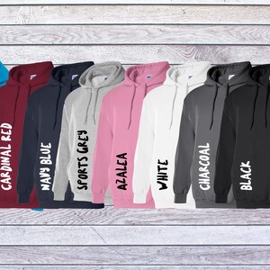 May include: A collection of eight hooded sweatshirts in various colors including sapphire, cardinal red, navy blue, sports grey, azalea, white, charcoal, and black. Each hoodie features a front pouch pocket, long sleeves, and a drawstring hood.