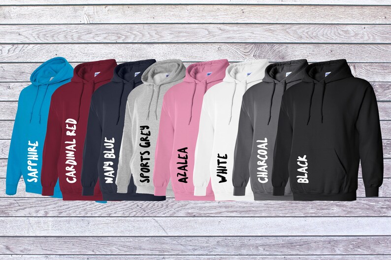 May include: A collection of eight hooded sweatshirts in various colors including sapphire, cardinal red, navy blue, sports grey, azalea, white, charcoal, and black. Each hoodie features a front pouch pocket, long sleeves, and a drawstring hood.