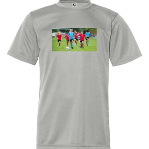 May include: A gray short-sleeved t-shirt with a graphic of a group of children playing soccer on a green field. The children are wearing blue and red jerseys.