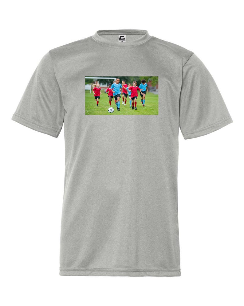 May include: A gray short-sleeved t-shirt with a graphic of a group of children playing soccer on a green field. The children are wearing blue and red jerseys.