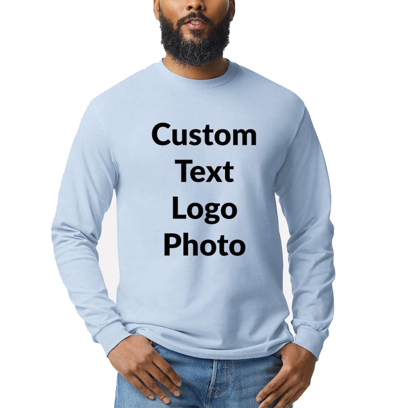 May include: A light blue long-sleeve crew neck shirt featuring the black printed text Custom Text Logo Photo centered on the chest. The garment has a standard fit with ribbed cuffs at the wrists and a simple round neckline design.