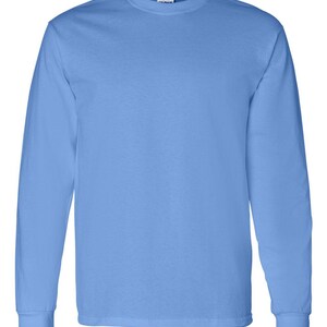 May include: A solid light blue long-sleeve t-shirt with a crew neckline and ribbed cuffs. The garment features a plain, unpatterned design with a visible brand label located at the inner back of the collar, providing a simple and clean aesthetic.