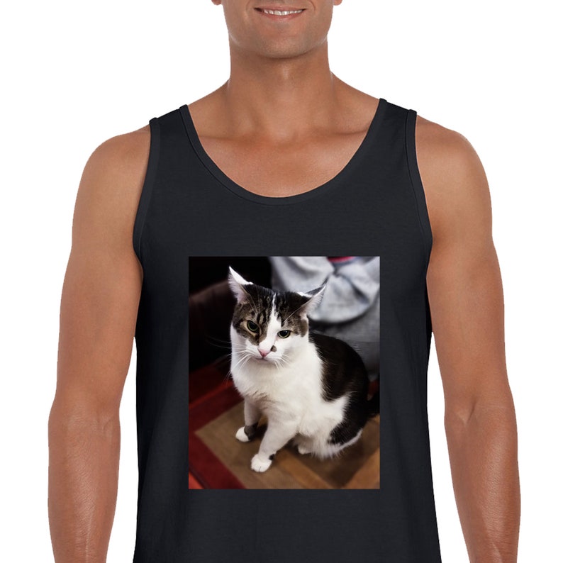Peut inclure: Un d&eacute;bardeur noir sans manches avec une impression graphique rectangulaire centr&eacute;e repr&eacute;sentant un chat tigr&eacute; blanc et brun fonc&eacute; avec une petite tache sombre sur le nez, assis face &agrave; l'avant avec les oreilles l&eacute;g&egrave;rement aplaties.