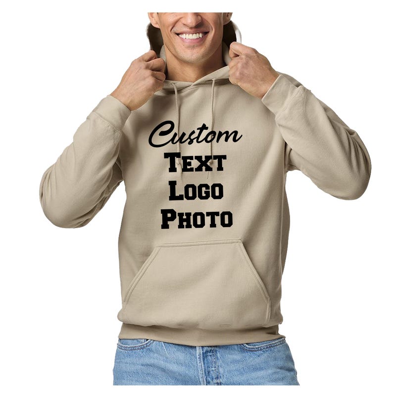 May include: A beige hooded sweatshirt featuring a front kangaroo pocket and long sleeves. The center of the chest displays the black text Custom TEXT LOGO PHOTO in a combination of script and block fonts. The garment includes a matching drawstring.