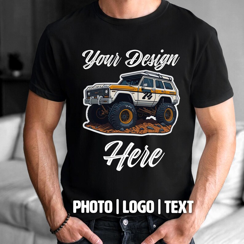 May include: Black t-shirt with a graphic of a white and yellow off-road vehicle with large tires. The text "Your Design Here" is above the vehicle, and "PHOTO | LOGO | TEXT" is below.