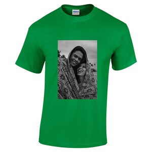 May include: Bright green t-shirt with a black and white photograph of two people smiling and wrapped in a patterned blanket. The shirt has a crew neck and short sleeves. The Gildan logo is visible on the upper right.