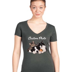May include: A dark charcoal gray V-neck t-shirt featuring a graphic print of a tabby cat, a black and white dog, and a small hamster huddled together. Above the animal group, the text Custom Photo is printed in a white, cursive script font.