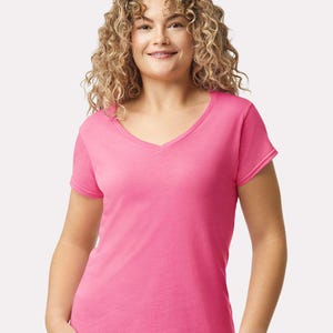 Op de afbeelding: Een felroze T-shirt met korte mouwen en een V-hals. Het kledingstuk is gemaakt van een eenvoudige, effen stof, wat zorgt voor een strakke en ongecompliceerde uitstraling die geschikt is voor diverse casual kledingcombinaties.