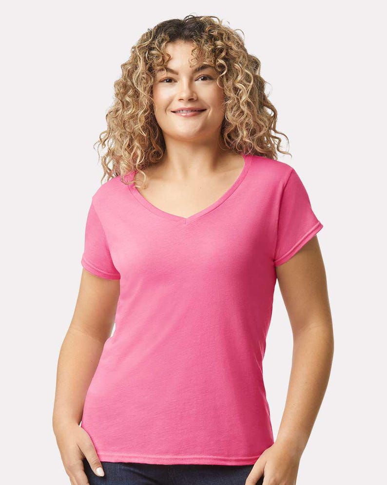 Op de afbeelding: Een felroze T-shirt met korte mouwen en een V-hals. Het kledingstuk is gemaakt van een eenvoudige, effen stof, wat zorgt voor een strakke en ongecompliceerde uitstraling die geschikt is voor diverse casual kledingcombinaties.