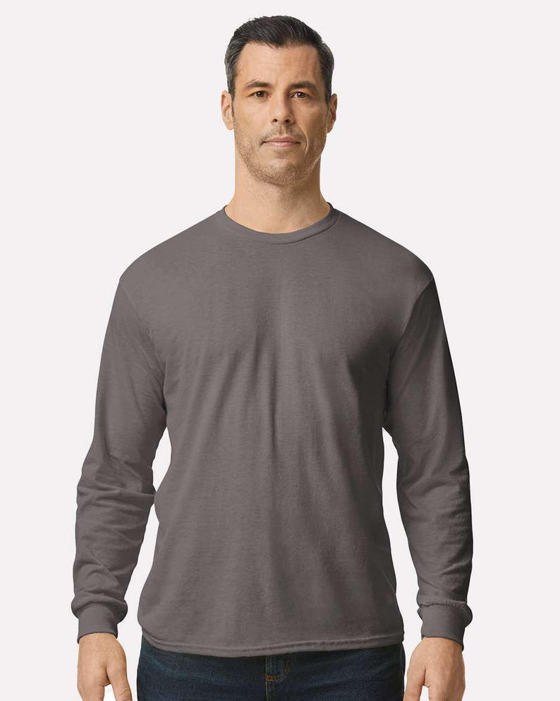 May include: A solid charcoal gray long-sleeve t-shirt with a crew neckline and ribbed cuffs. The garment features a standard fit with a straight hemline, constructed from a smooth, opaque fabric that provides full coverage for the torso and arms.