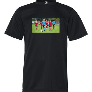 May include: A black t-shirt with a graphic of a group of children playing soccer on a green field. The children are wearing red and blue uniforms. The graphic is centered on the t-shirt.
