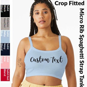 May include: A light blue crop top with thin spaghetti straps. The top is made of a ribbed fabric and has the text "Custom Text" printed on the front.