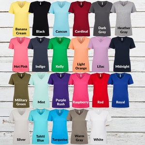 May include: A collection of twenty-three short-sleeve V-neck t-shirts in various solid colors including banana cream, black, cancun, cardinal, dark grey, heather gray, hot pink, indigo, kelly, light orange, lilac, midnight, military green, mint, purple rush, raspberry, red, royal, silver, tahiti blue, turquoise, warm gray, and white.
