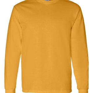 May include: A solid gold-colored long-sleeve t-shirt with a crew neckline and ribbed cuffs. The garment features a plain, unpatterned design with a standard fit, showcasing a consistent mustard yellow hue throughout the entire fabric surface.