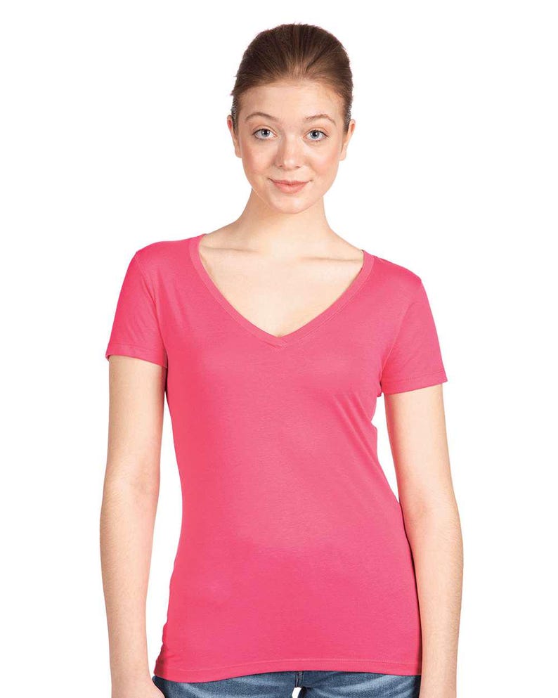 May include: A bright pink short-sleeved t-shirt featuring a deep V-neckline. The garment is constructed from a solid-colored fabric with a smooth texture, short sleeves, and a straight hemline that sits at the waist, providing a simple design.