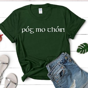 May include: A dark green t-shirt with white text that reads "póg mo chón".