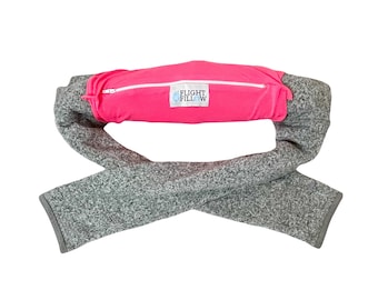 May include: A travel pillow with a bright pink center section and gray sleeves. The pink section has a zipper and the text "FLIGHT FILL W". The sleeves are a speckled gray fabric, and the pillow is designed to be worn around the neck.