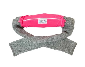 May include: A gray fleece travel pillow with a pink zippered pocket that says "FLIGHT FILLOW" in white.