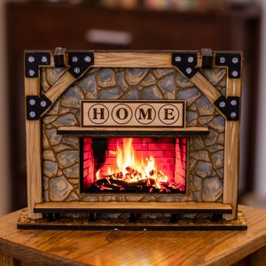 Puede incluir: Una chimenea de madera con una fachada de piedra y una chimenea encendida. La chimenea tiene un letrero que dice "HOME" sobre la chimenea.