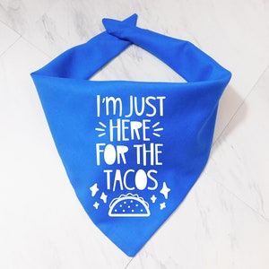 Op de afbeelding: Blauwe bandana met witte tekst die "Ik ben hier alleen voor de taco's" zegt en een witte omtrek van een taco.