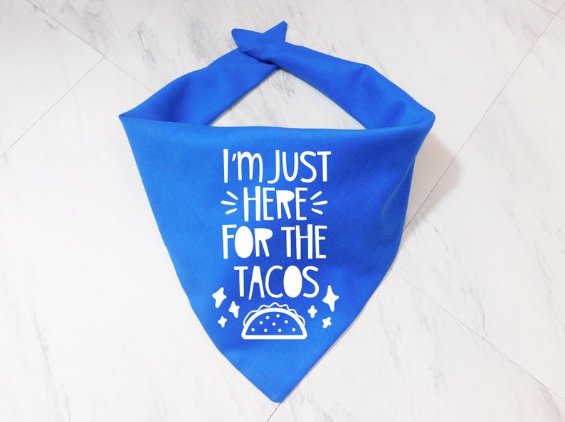 Op de afbeelding: Blauwe bandana met witte tekst die "Ik ben hier alleen voor de taco's" zegt en een witte omtrek van een taco.