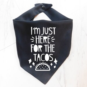 Op de afbeelding: Zwarte bandana met witte tekst die "Ik ben hier alleen voor de taco's" zegt en een witte omtrek van een taco.