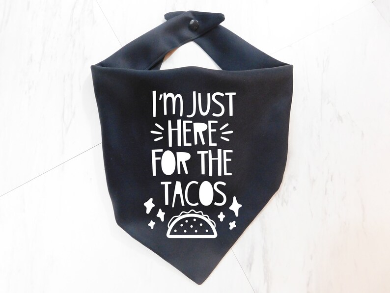 Op de afbeelding: Zwarte bandana met witte tekst die "Ik ben hier alleen voor de taco's" zegt en een witte omtrek van een taco.