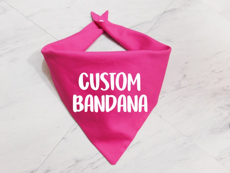 May include: A pink bandana with the text "CUSTOM BANDANA" in white.