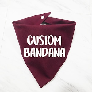 May include: A burgundy bandana with the text "CUSTOM BANDANA" printed in white.