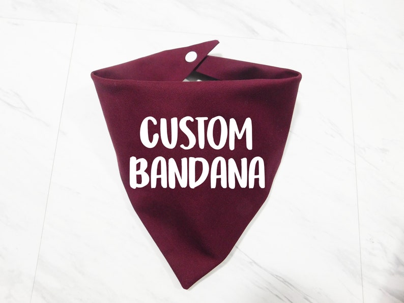 May include: A burgundy bandana with the text "CUSTOM BANDANA" printed in white.