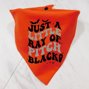 May include: Orange bandana with a black and gray design that says "Just a little ray of pitch black" with a bat and a cross graphic.