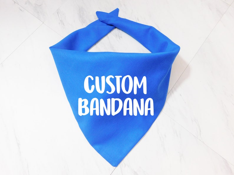 May include: A bright blue bandana with the text "CUSTOM BANDANA" printed in white.
