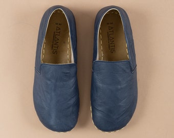 May include: A pair of blue leather slip-on shoes with the word "ATLANTIS" printed on the inside of each shoe.