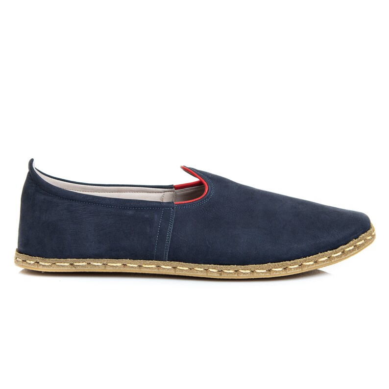 May include: A pair of dark blue suede slip-on shoes with a red trim around the opening and a light brown jute sole.