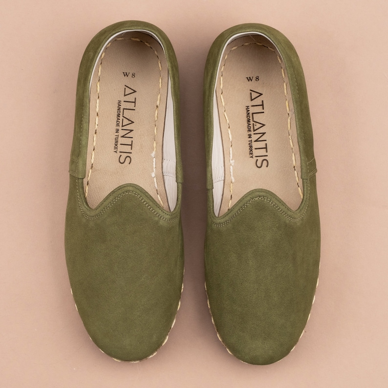 Pu&ograve; includere: Un paio di scarpe da uomo in camoscio verde da indossare senza lacci con un'etichetta "W 8 ATLANTIS HANDMADE IN TURKEY" all'interno.