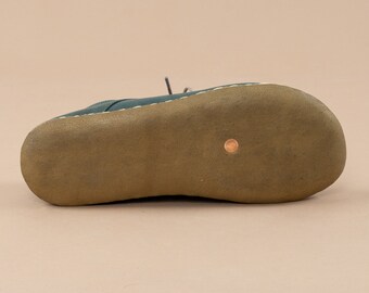 May include: The bottom of a dark green leather shoe with a brown rubber sole.