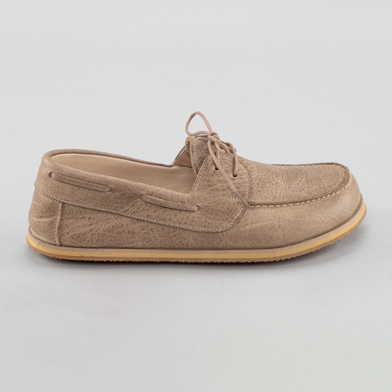 Pu&ograve; includere: Una singola scarpa da barca beige con tomaia in pelle strutturata e suola colorata chiara. La scarpa presenta una chiusura con lacci e dettagli di cucitura visibili. Il design generale &egrave; casual e adatto all'uso quotidiano.