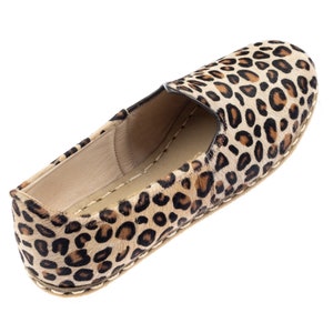 May include: Leopard print slip-on shoe with a brown leather sole.