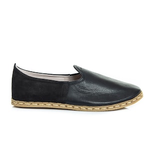 May include: Black leather slip-on shoes with a suede heel and a brown stitched sole.