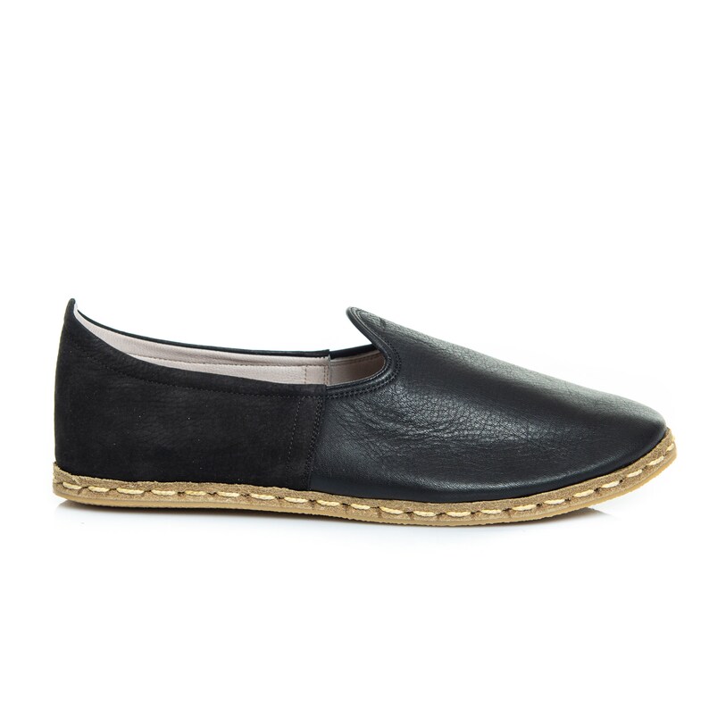 May include: Black leather slip-on shoes with a suede heel and a brown stitched sole.