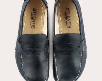 May include: A pair of black leather loafers with a white stitch detail around the edge. The loafers have a simple design with a single strap across the top. The inside of the shoes are lined with a tan leather and have the text "ATLANTIS HANDMADE IN TURKEY" printed on the insole.