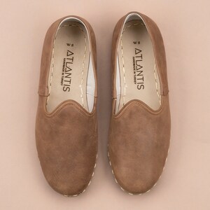 Puede incluir: Un par de zapatos marrones de cuero con un borde cosido. Los zapatos tienen una etiqueta blanca en el interior que dice "ATLANTIS HANDMADE IN TURKEY W 8".