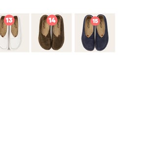May include: Three pairs of slip-on shoes are displayed. The first pair is white, the second is brown, and the third is navy blue. Each pair has a rounded toe and a small red heart detail. The brand name "ATLANTIS" is visible on each shoe.
