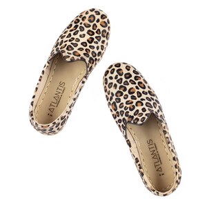 May include: A pair of brown and black leopard print slip-on shoes with the text "ATLANTIS HANDMADE IN TURKEY" on the inside of each shoe.