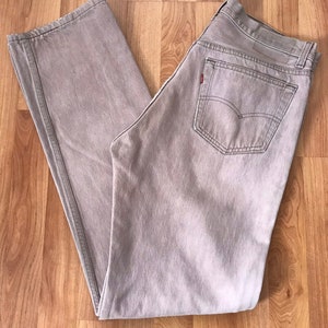 May include: A pair of light brown denim jeans with a back pocket featuring a red Levi's logo.