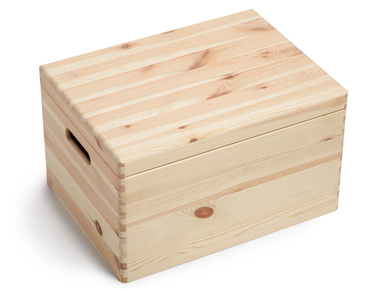 May include: A rectangular wooden storage box with a lid. The box is constructed from light-colored, unfinished wood planks. It features a handle cut-out on one side and is suitable for storing various items. The box is designed with a simple, natural aesthetic.