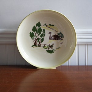May include: A vintage white ceramic bowl with a yellow rim features a hand-painted scene of a farmhouse with a red roof, a windmill, and a horse-drawn cart in a green field.